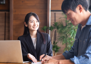 若い女性のスタッフが会議室で男性をサポートしている様子