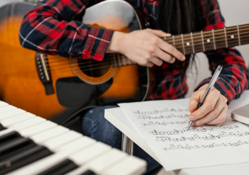 男性がギターを抱えながら楽譜を書いている様子