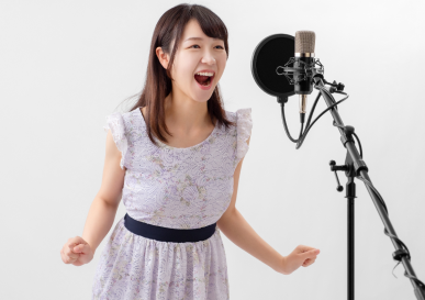 女性がマイクに向かって全力で歌っている様子