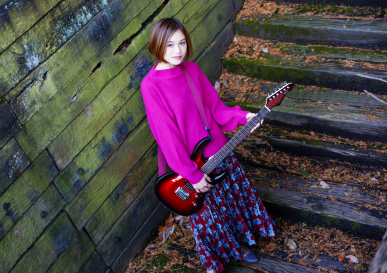 ピンクの服を着た女性が階段でギターを持っている様子